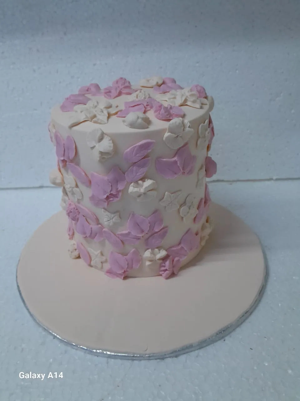 Customize cake with pink and white floral decorations on a white surface
