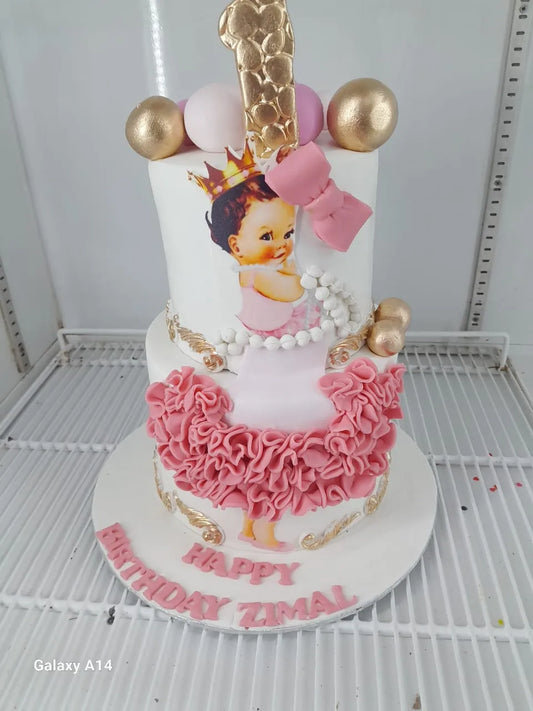 Birthday cake with a baby girl design and pink ruffles, featuring balloons and 'Happy Birthday Tiaal' text.