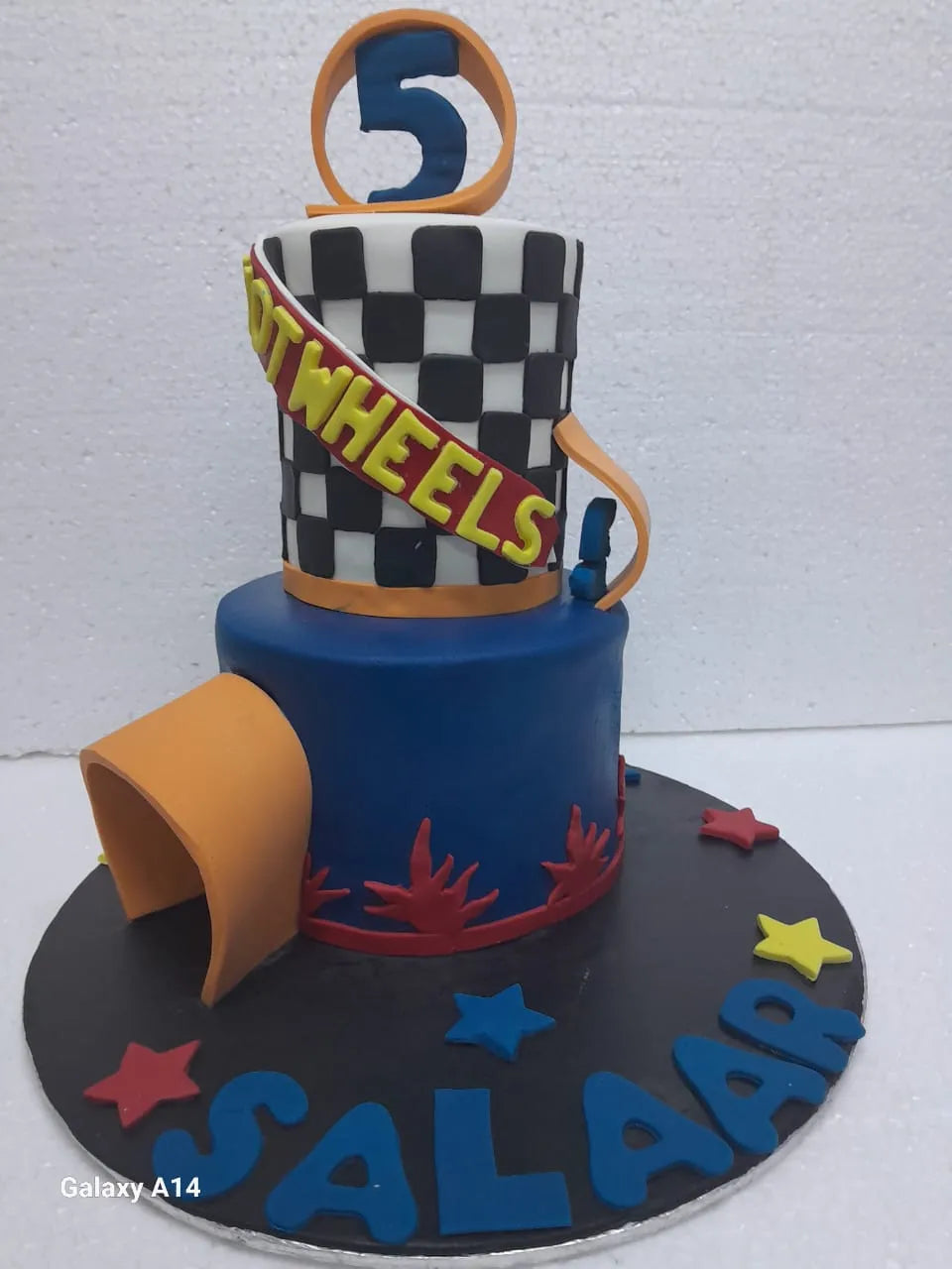 Children's birthday cake with racing theme and number 5 on top, against a white background.
