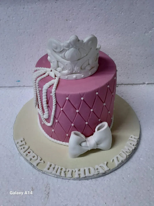 Pink birthday cake with a white crown and bow on a white background
