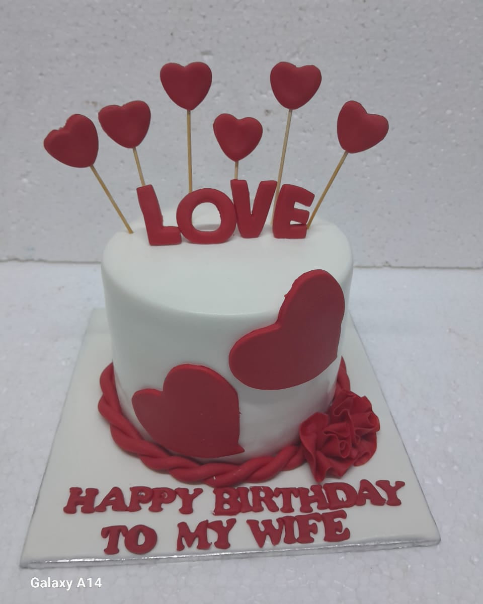 Small white cake with red hearts and 'LOVE' letters on a white background