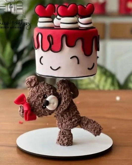 Cake with a teddy bear and red heart decorations on a wooden table.