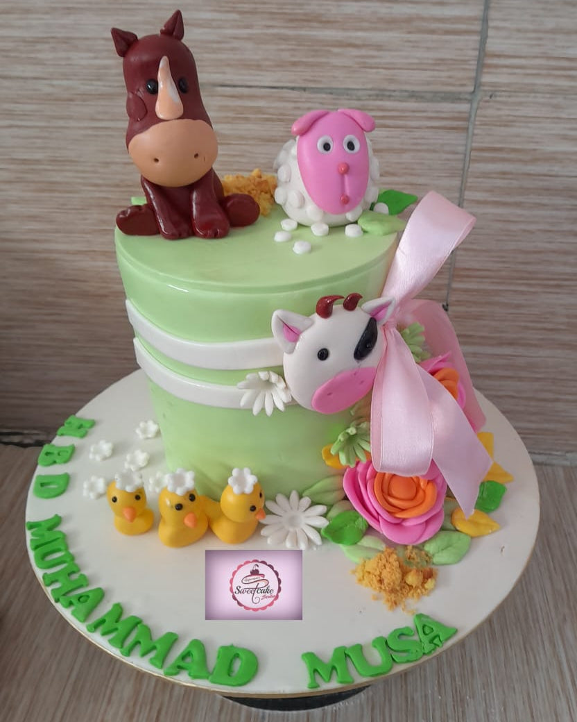 Two-tiered cake with animal figurines and colorful decorations on a wooden surface.