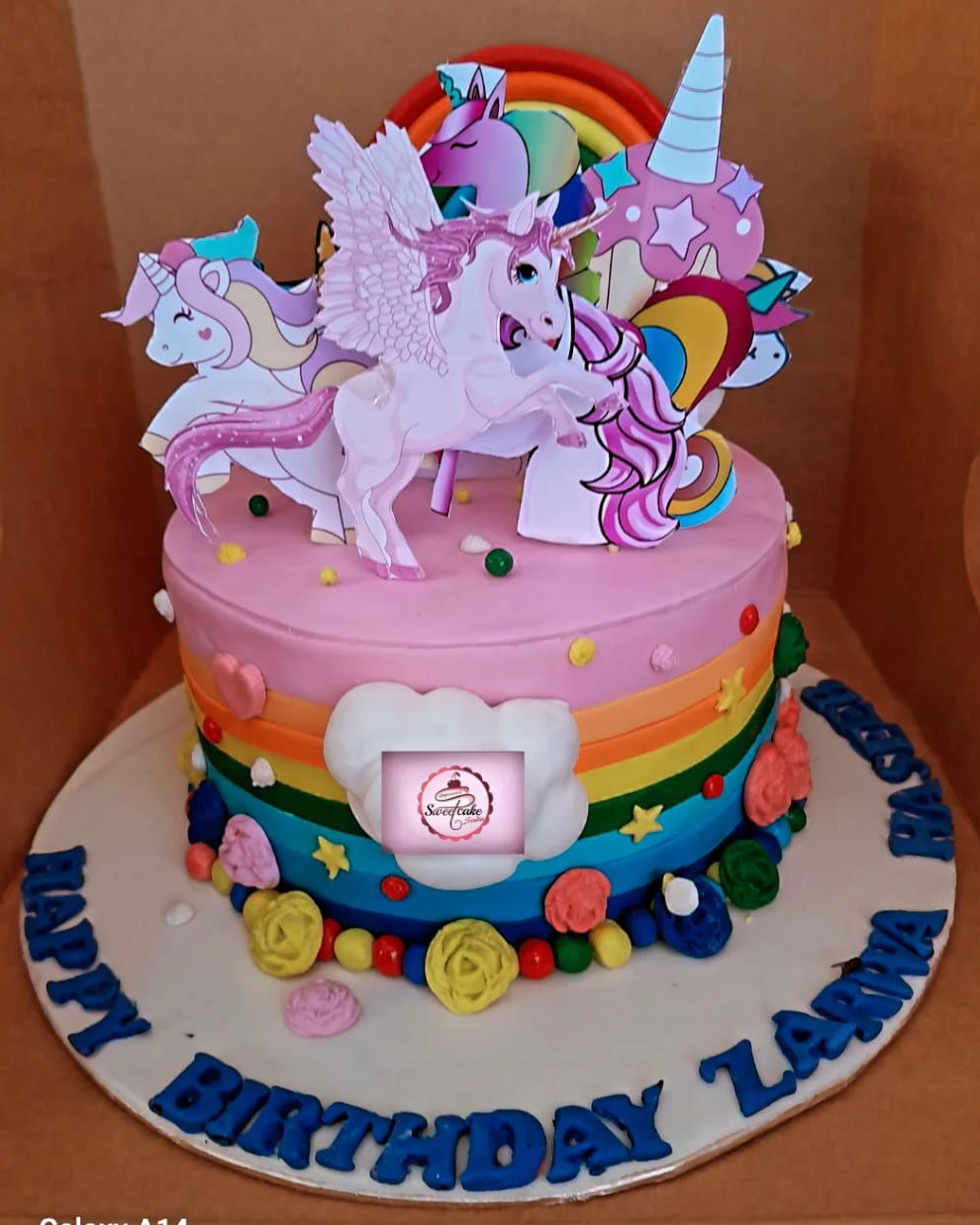 Colorful birthday cake with unicorn toppers on a plain background